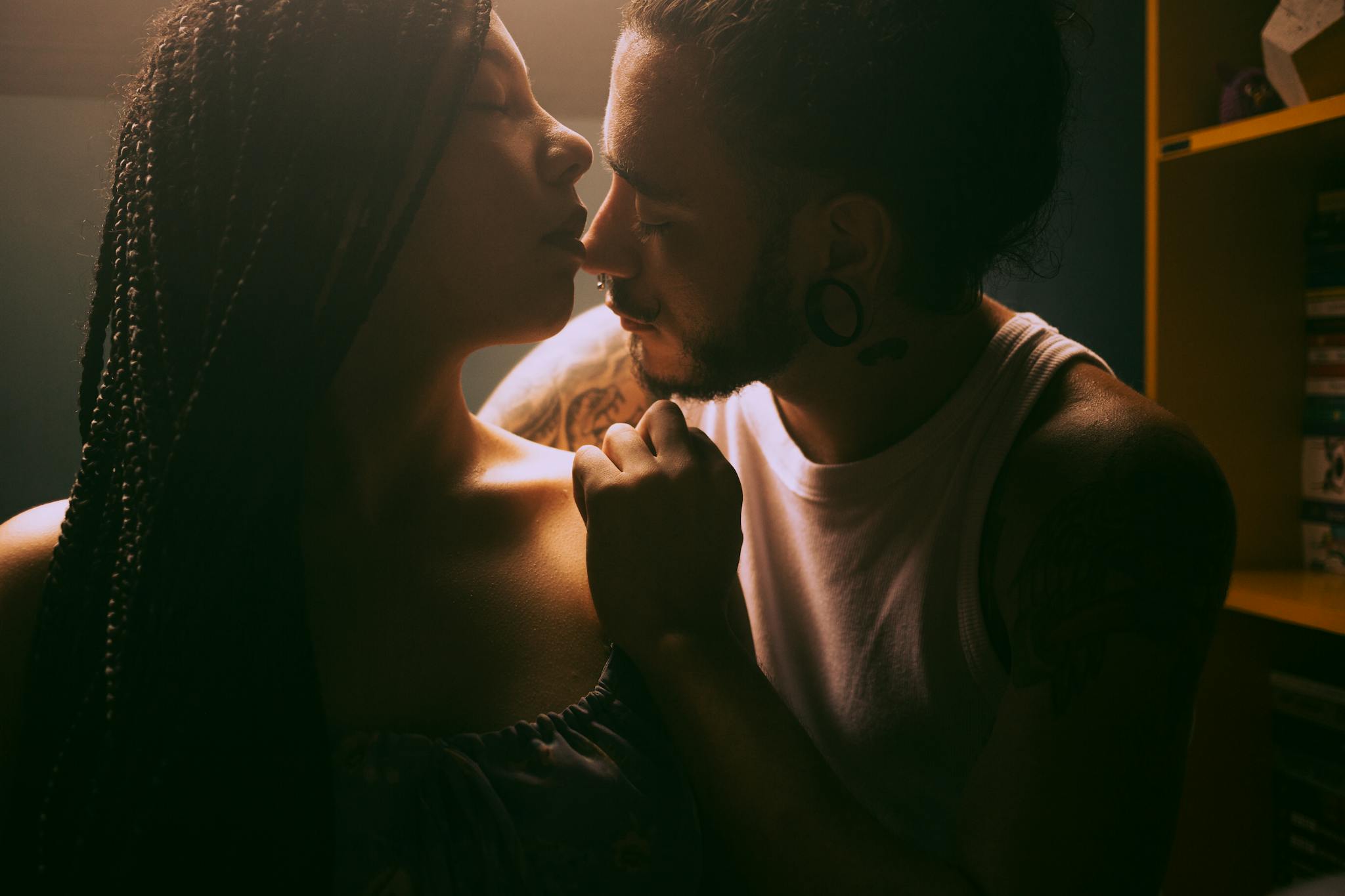 A young couple shares an intimate, romantic moment indoors with soft lighting.