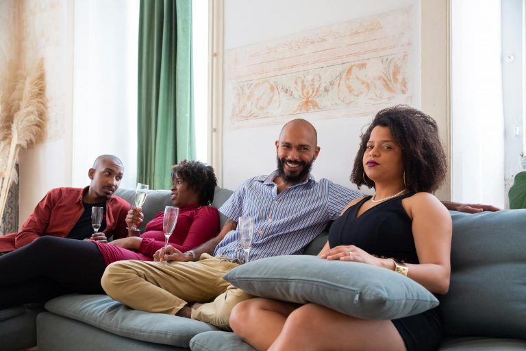 Group of friends relaxing on the couch with wine at an indoor home party in Portugal.