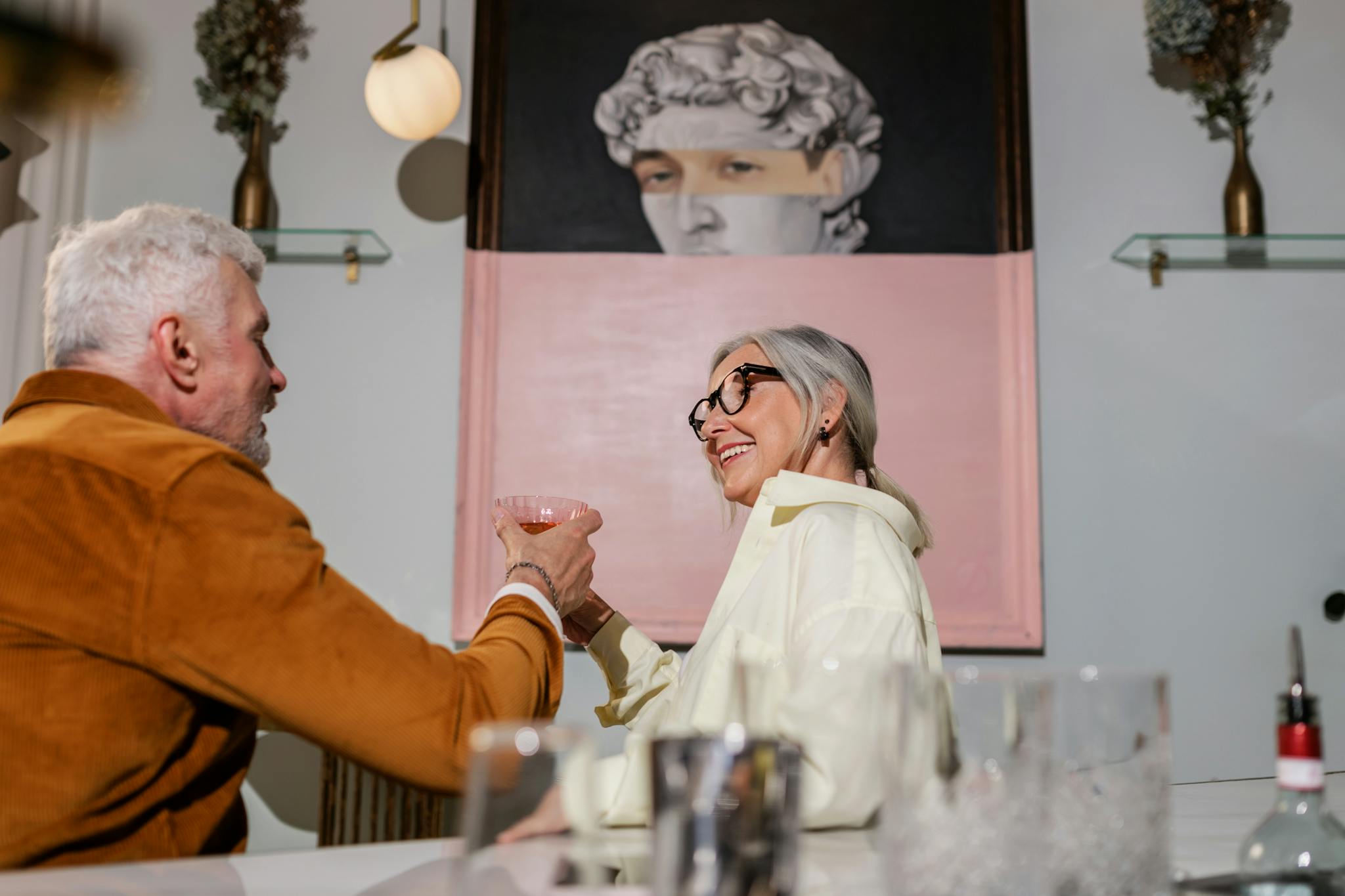 Senior couple enjoying a cheerful toast in a stylish indoor setting.